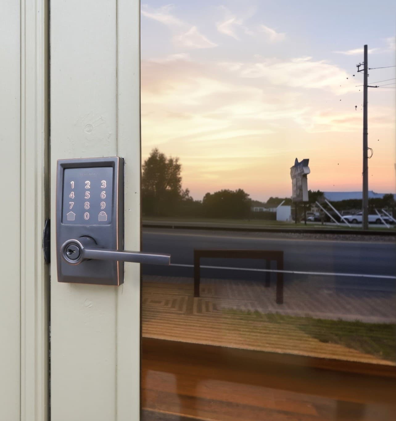 A close-up of a digital door lock with an evening sky reflected in the glass.